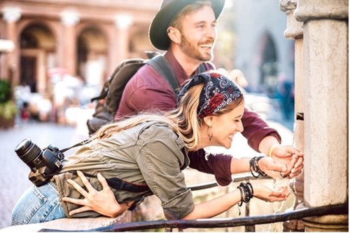 Zwei Personen trinken aus einem Trinkbrunnen