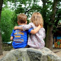 Zwei Kinder sitzen Arm in Arm auf einem Stein